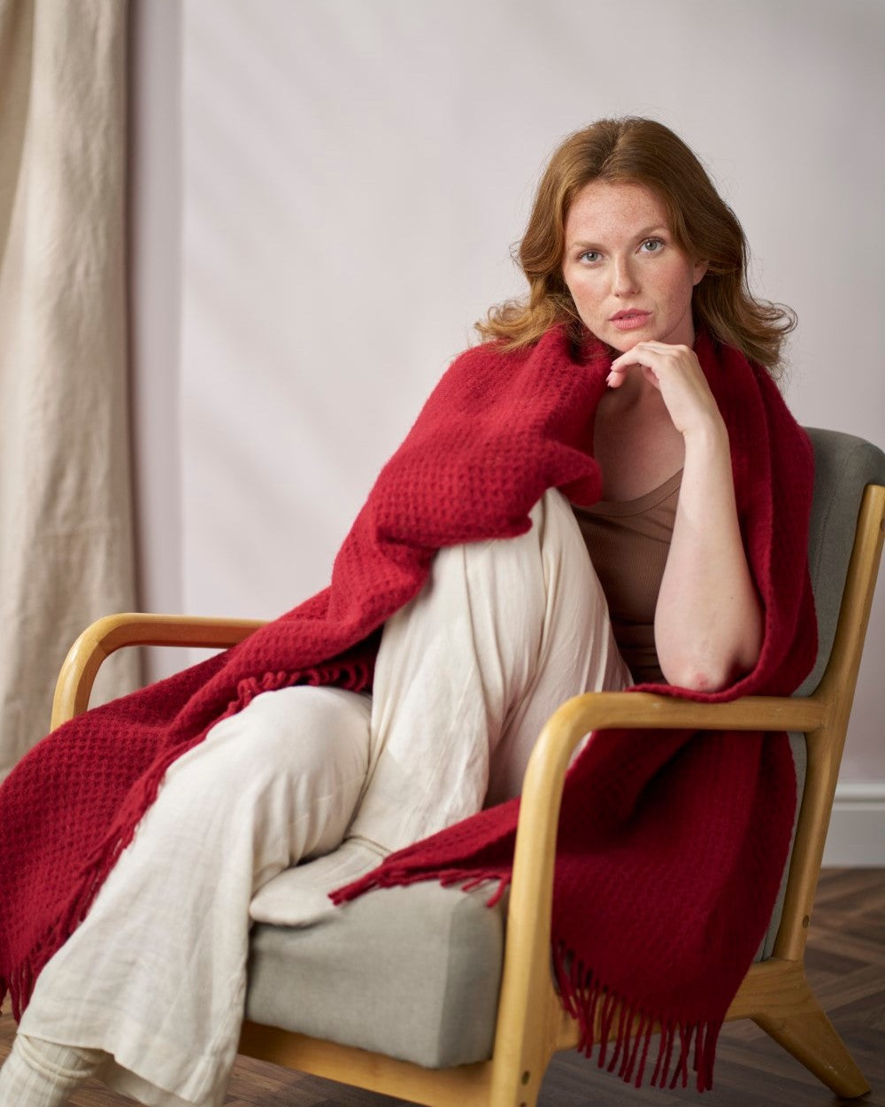 Woman in armchair with Bright Friday Blanket Bundle: Air Balloon draped over her shoulders and lap, showcasing its textured design.