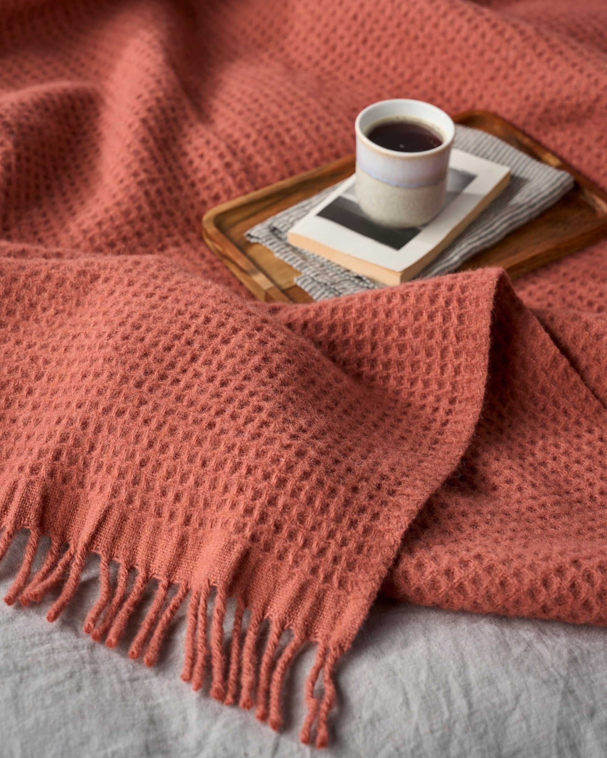 Bright Friday Blanket Bundle: Brunswick displayed with a waffle-weave throw, fringed edges, accompanied by a wooden tray holding a ceramic mug and a paperback book.