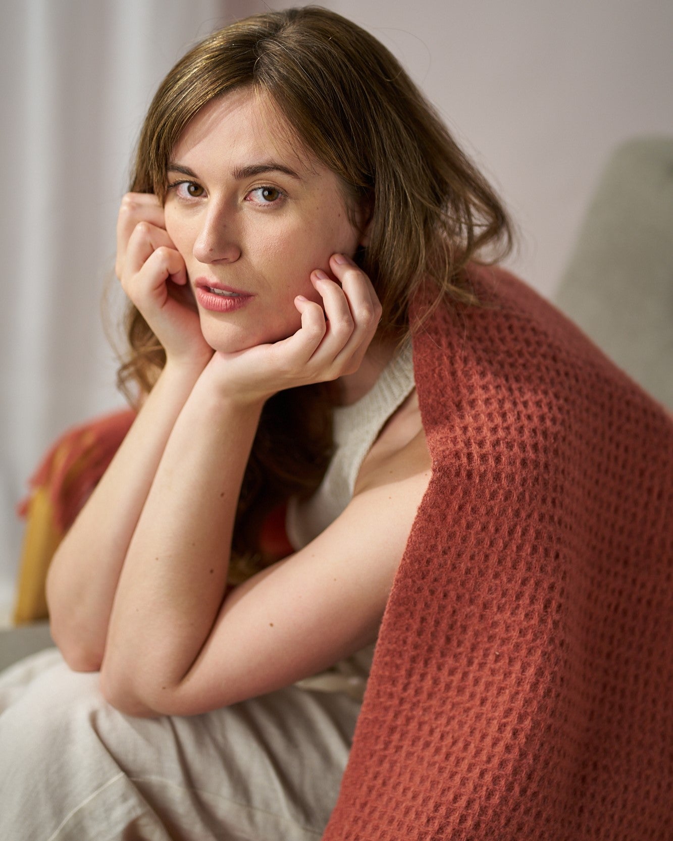 Young woman in a sleeveless top, wrapped in the textured Bright Friday Blanket Bundle: Brunswick, gazes contemplatively at the camera.