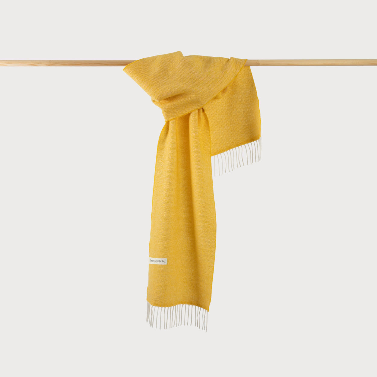 Herringbone Scarf: Sunflower, draped over a wooden bar, showcasing its fine herringbone pattern and soft texture.
