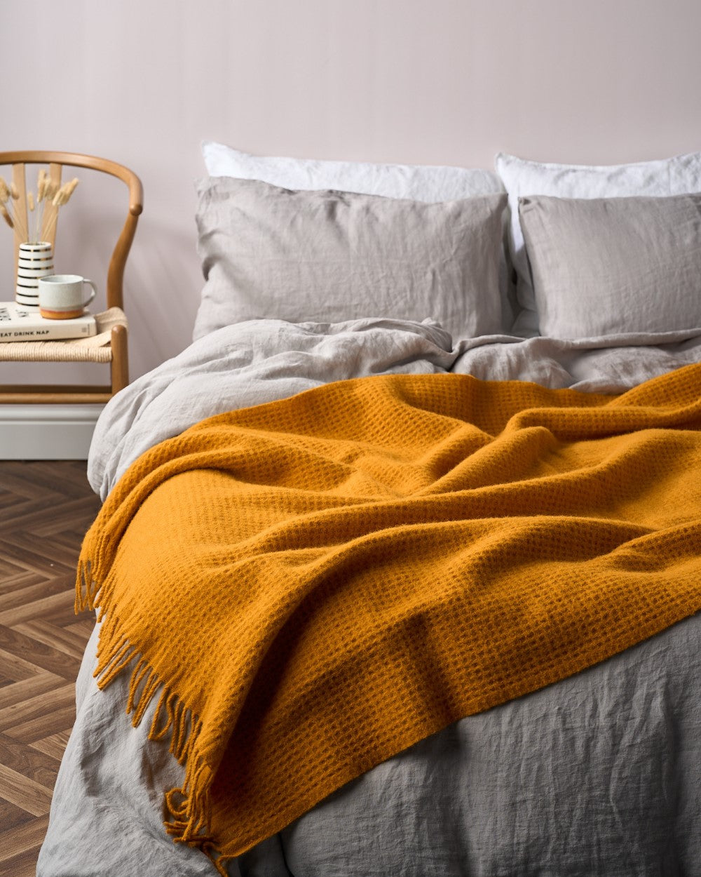 Bright Friday Blanket Bundle: Ashton draped over bed, featuring a textured throw. Accompanied by a wooden chair nightstand with a vase, mug, and book.