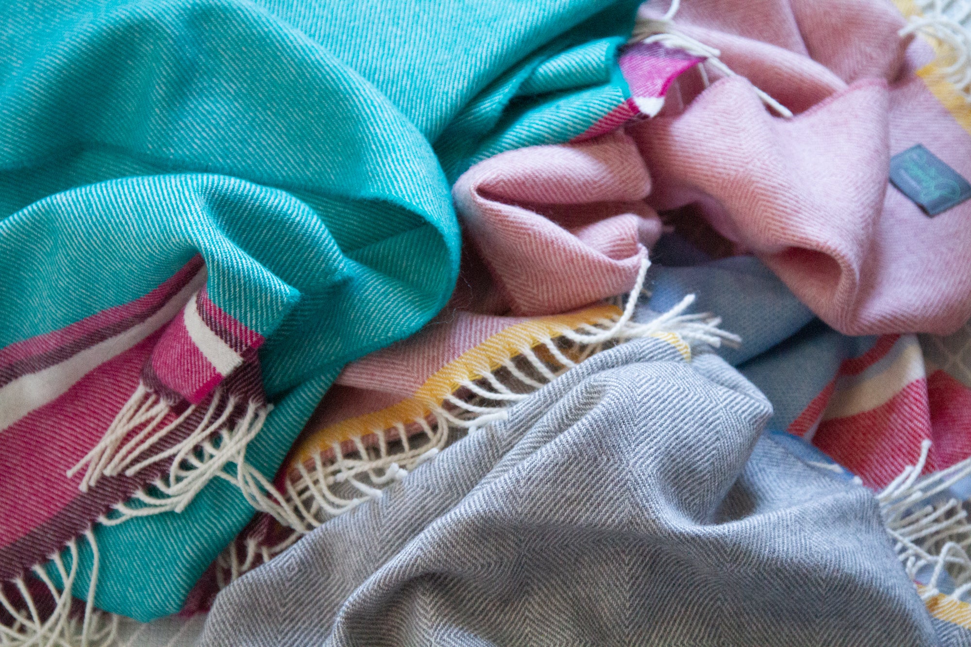 A pile of wool baby blankets in various colours.