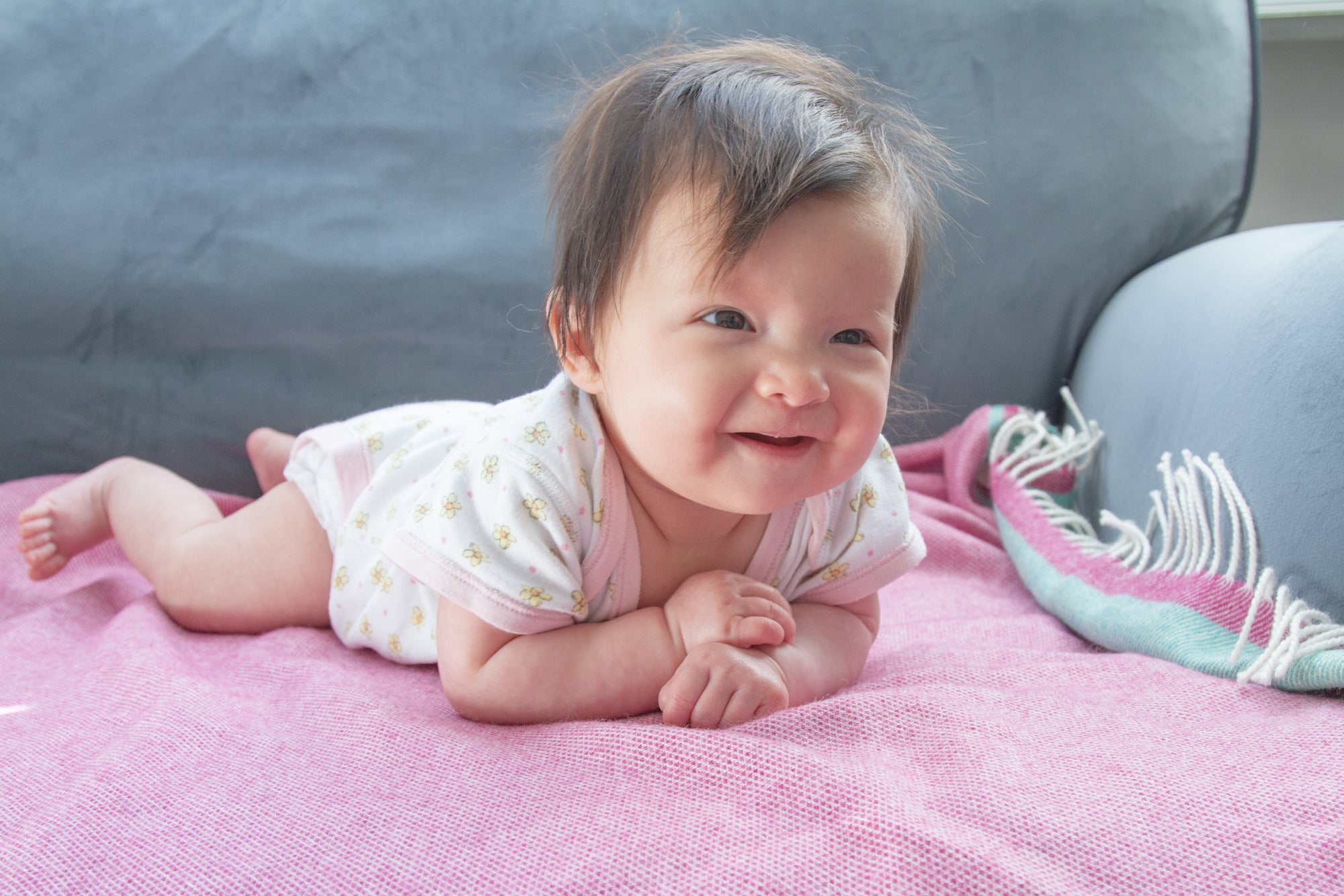 A baby lying chest down on a pink and blue lambswool baby blanket