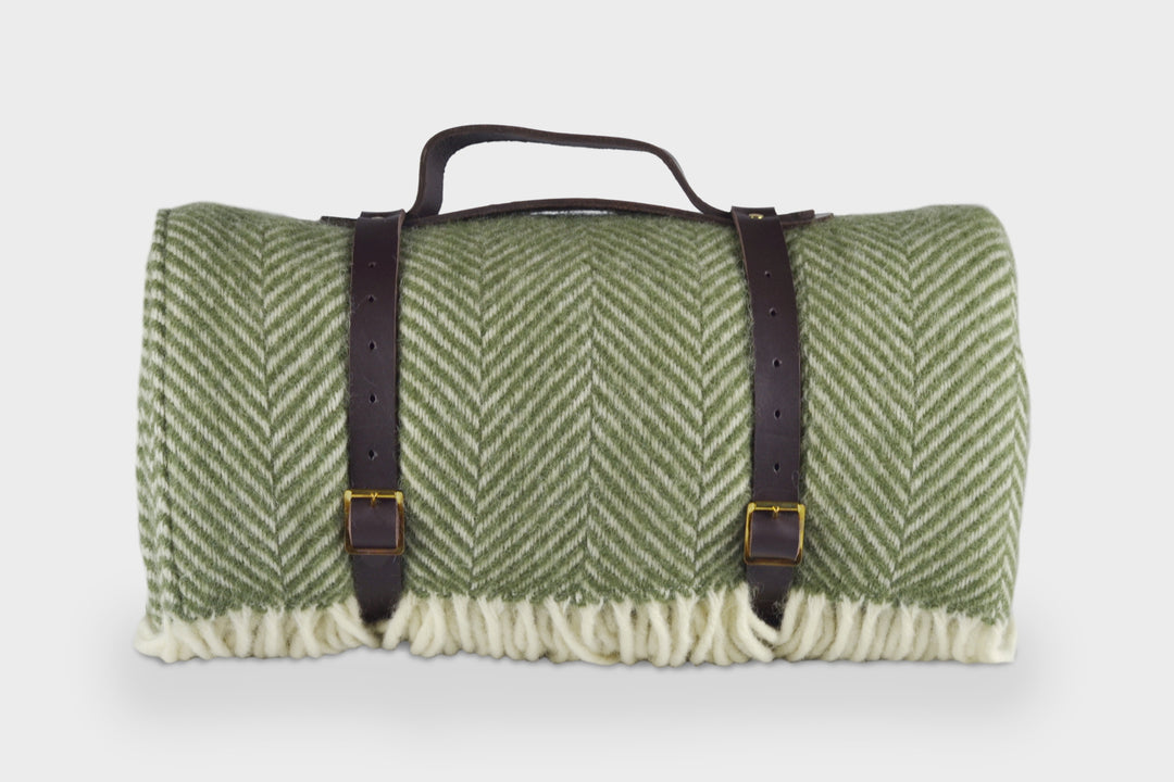 Green picnic rug by The British Blanket Company rolled up with leather straps