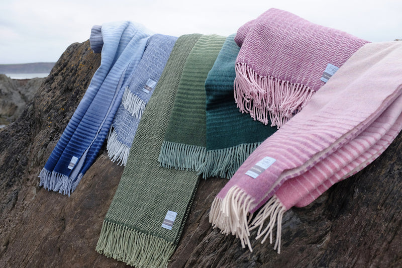 Seven wool blankets from the Shipping Forecast collection folded over a rock formation