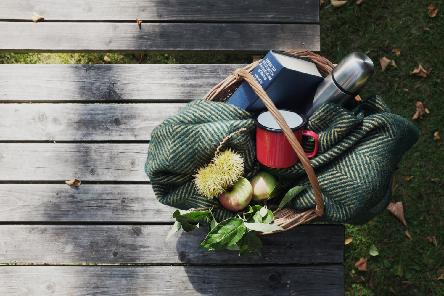 Green wool blanket from british blanket company in a wicker basket for an autumn picnic 