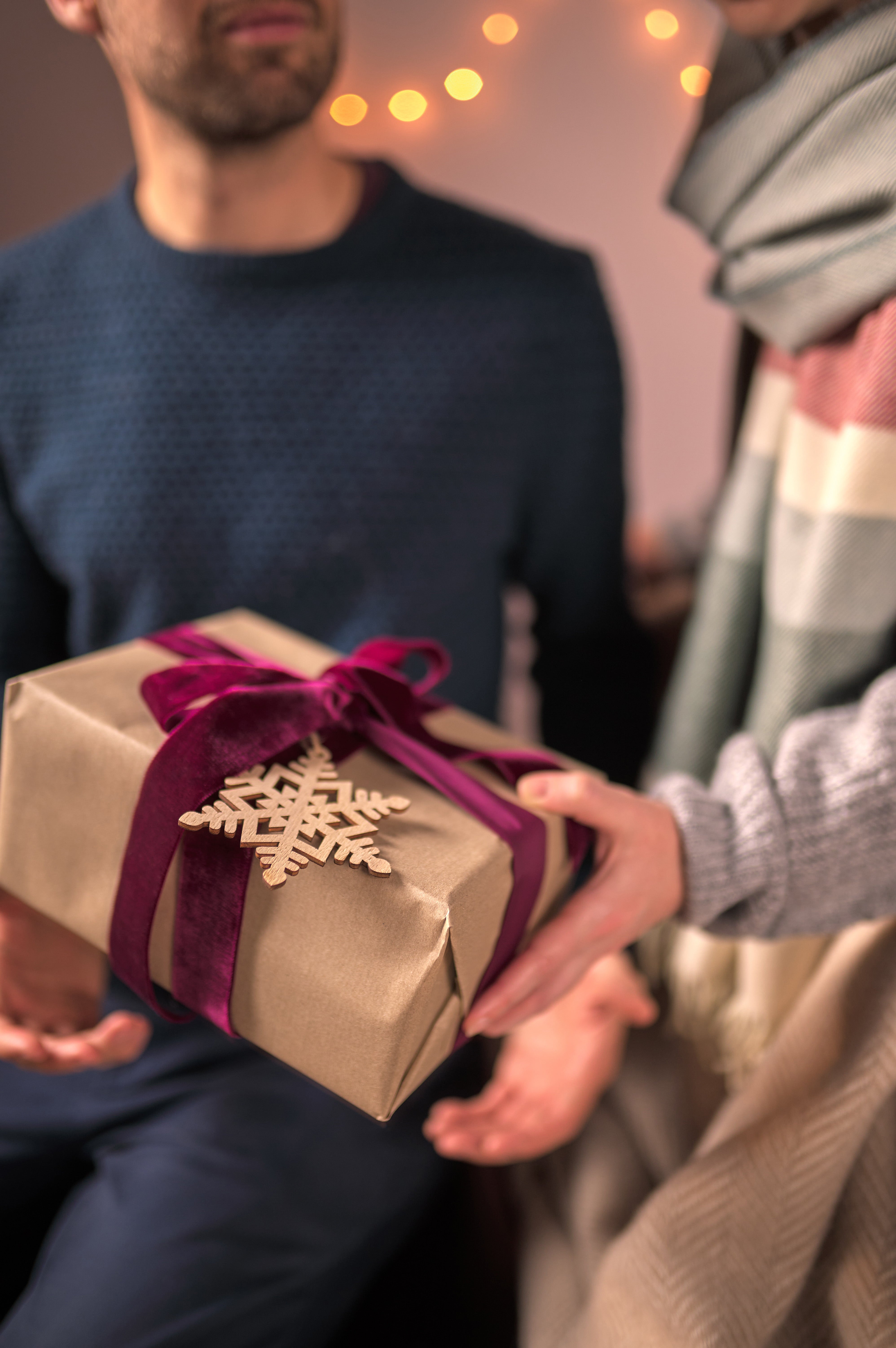 A man wearing a scarf and a buttoned jacket, looking upward. Close-up highlights facial details and the scarf's fringe.