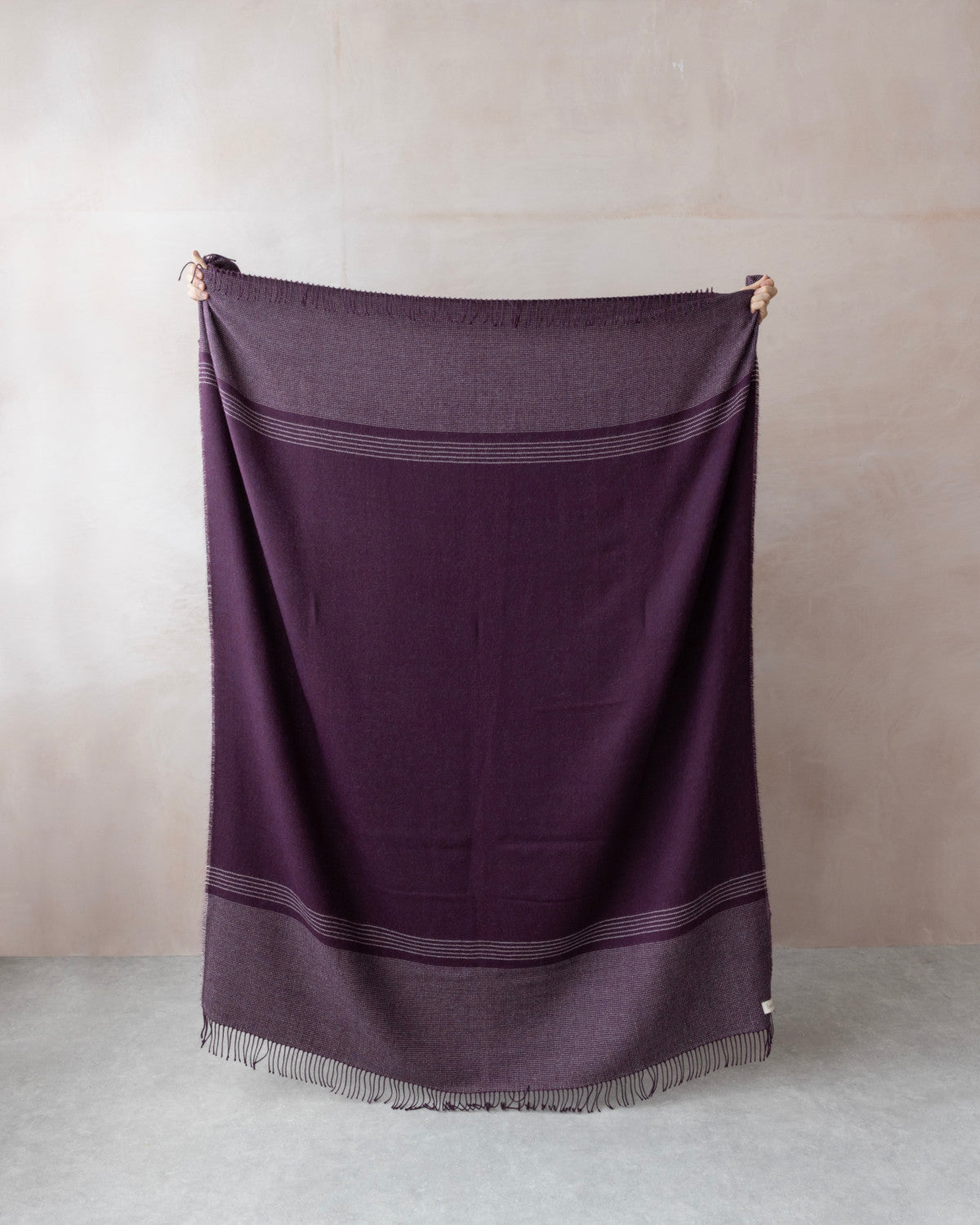 Alpaca Blanket Gift Box: Berry Purple featuring a large woven throw with fringe, subtle stripe detailing, and presented with a candle and chocolate in a gift box.