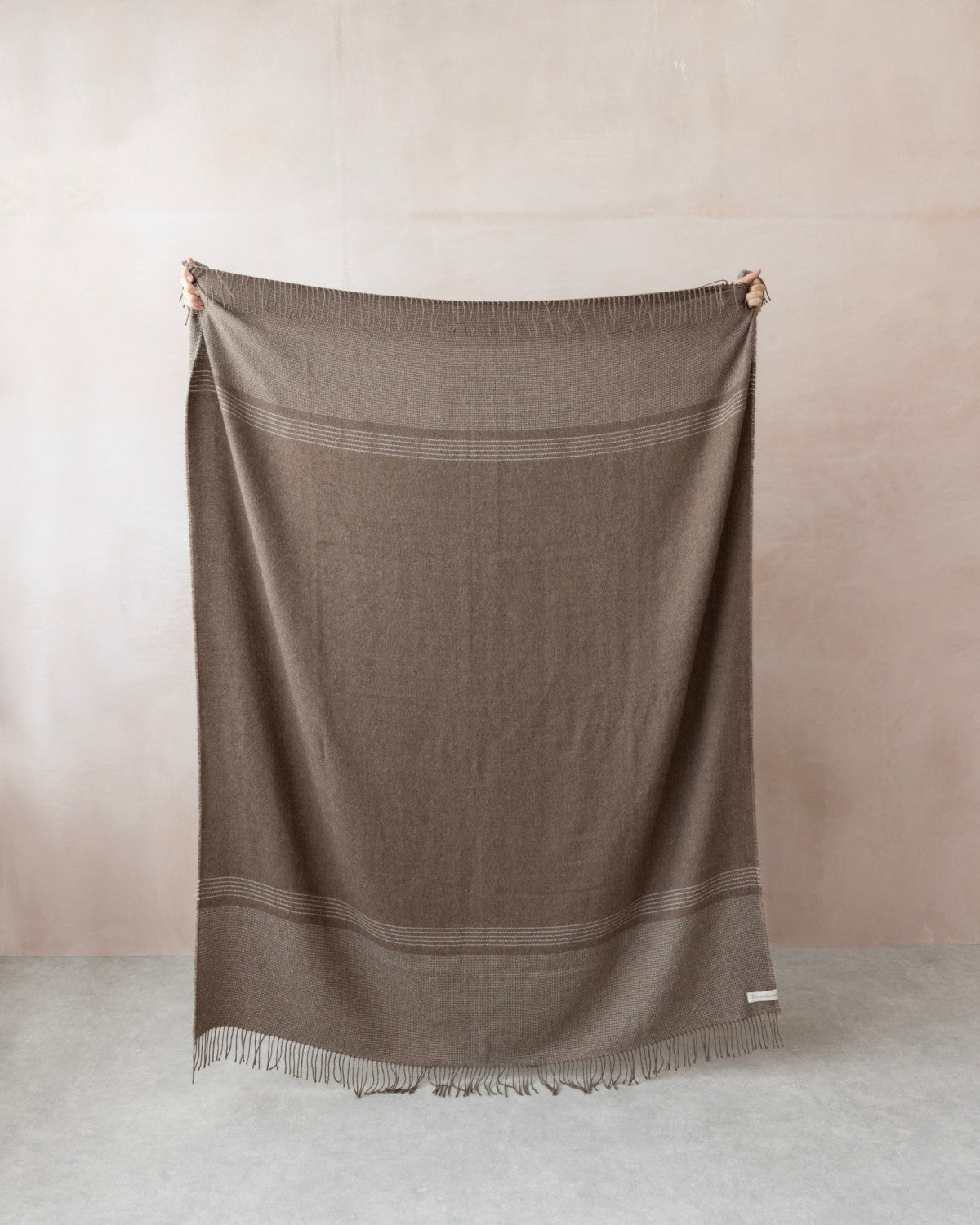 Alpaca Blanket Gift Box: Mocha Brown features a large, muted brown throw with fringe and stripe details, shown fully stretched against a neutral backdrop.