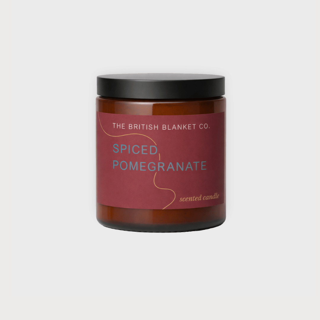 Amber Jar Candle: Spiced Pomegranate in amber glass with black lid, featuring The British Blanket Co. label, offering a warm, spiced pomegranate fragrance.