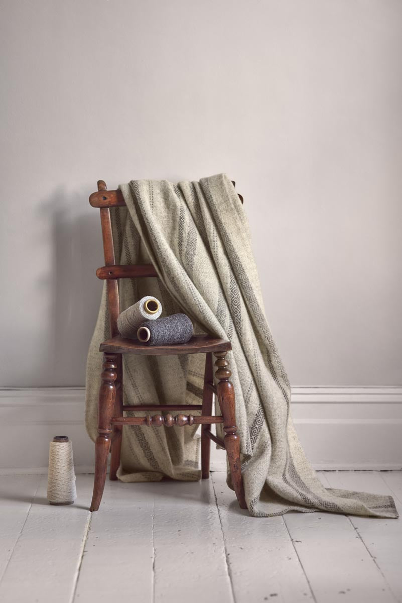 British Wool Natural Stripe Blankets and Cushions draped on a chair