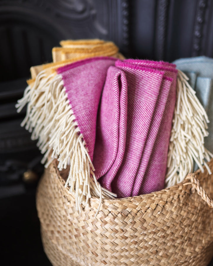 Pink, blue and yellow merino wool throws in basket from The British Blanket Company