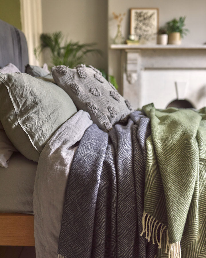 bed styled with grey and olive green wool throw blankets from The British Blanket Company online shop