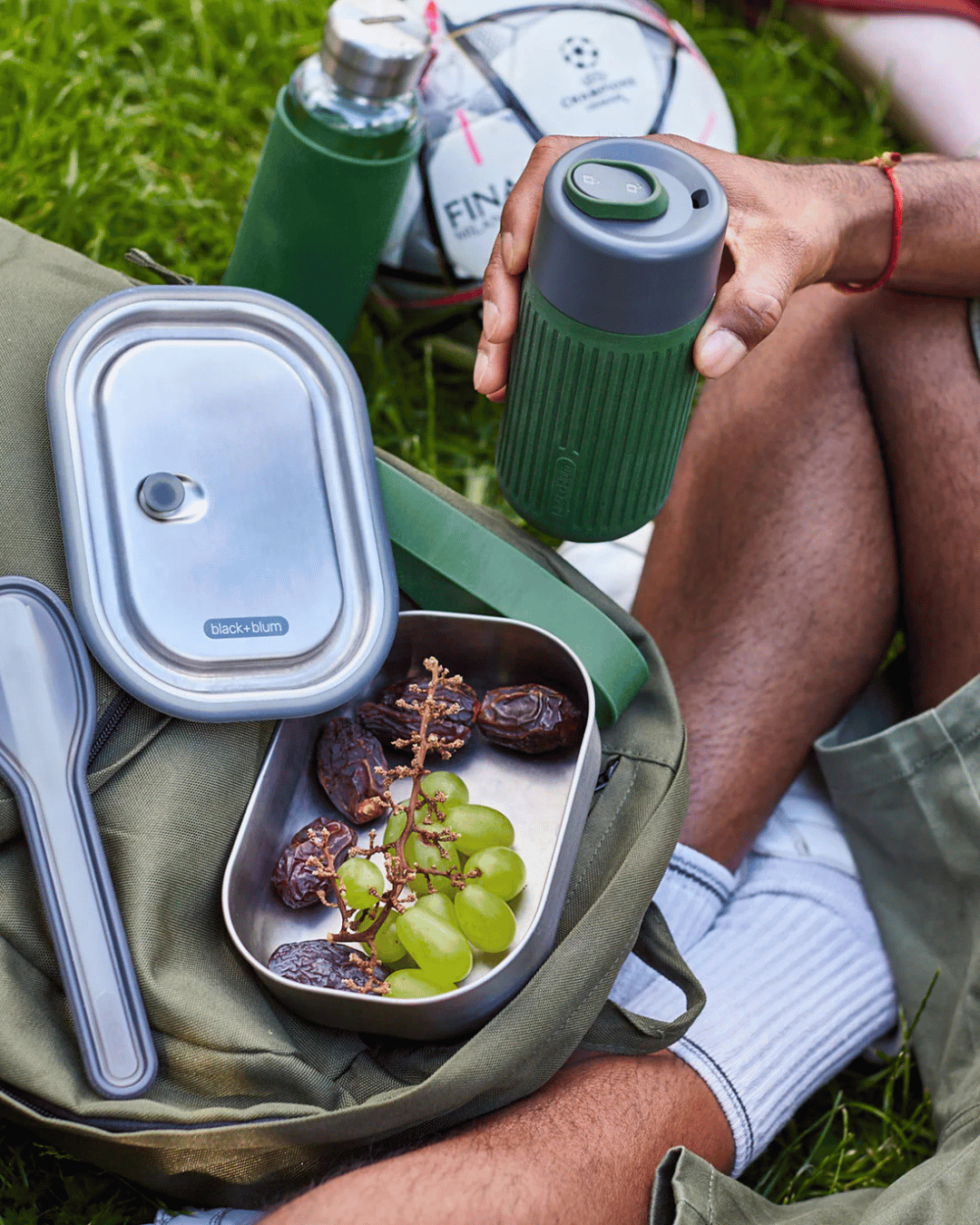 Person having a picnic in the park, with the Black + Blum Lunch Box