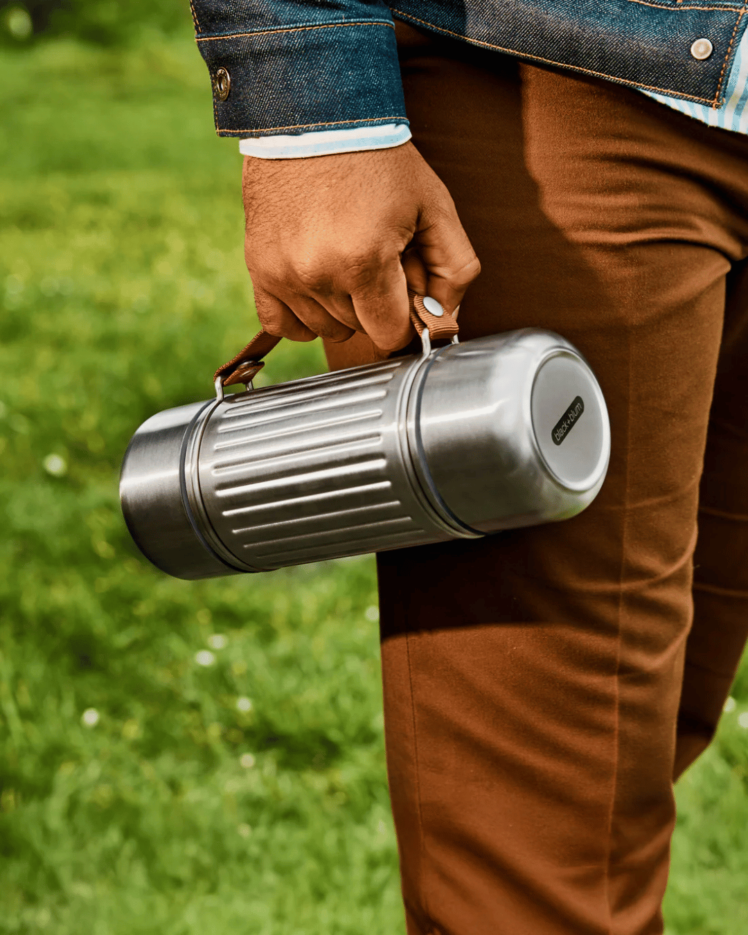 Person walking with the Black + Blum flask 