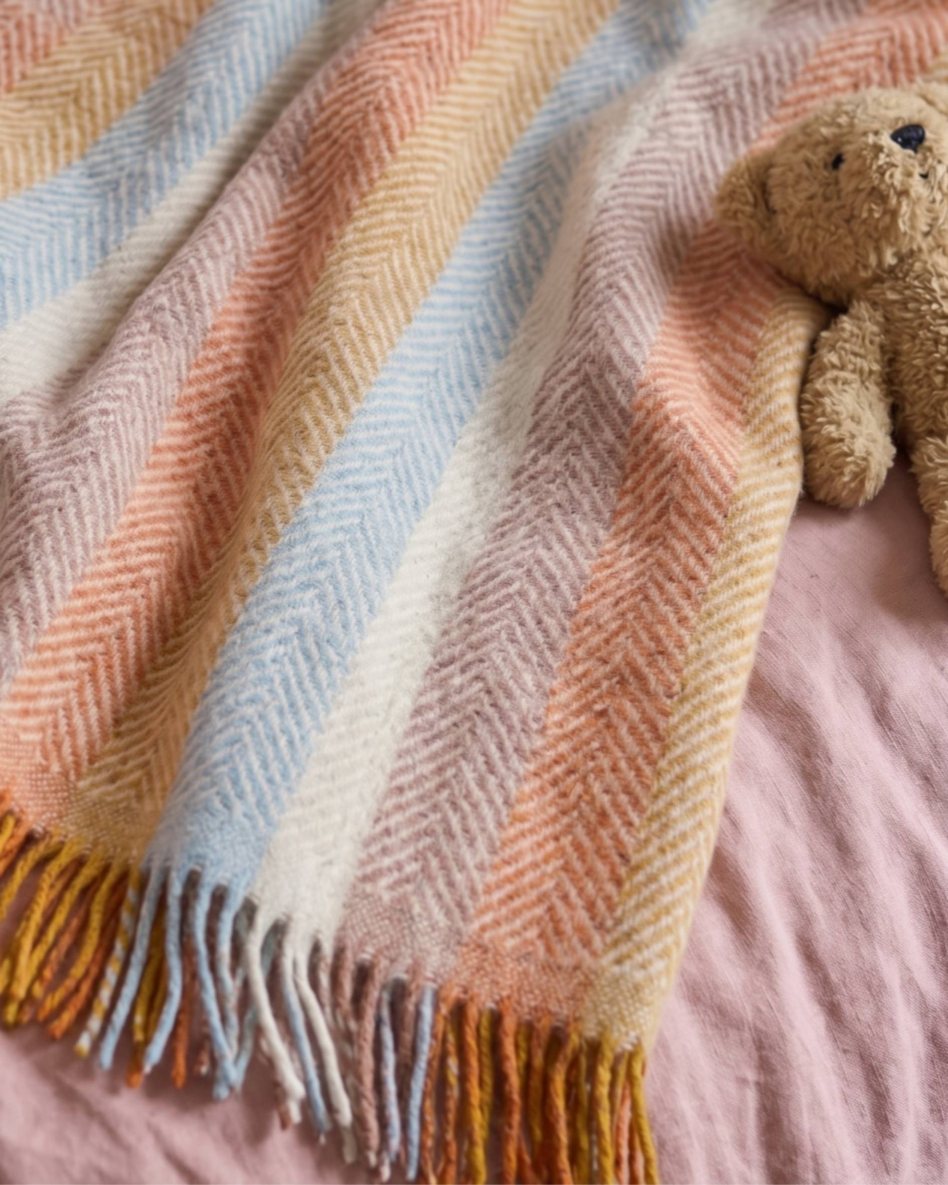 Rainbow Stripe Boho Kids Blanket with a childs teddy