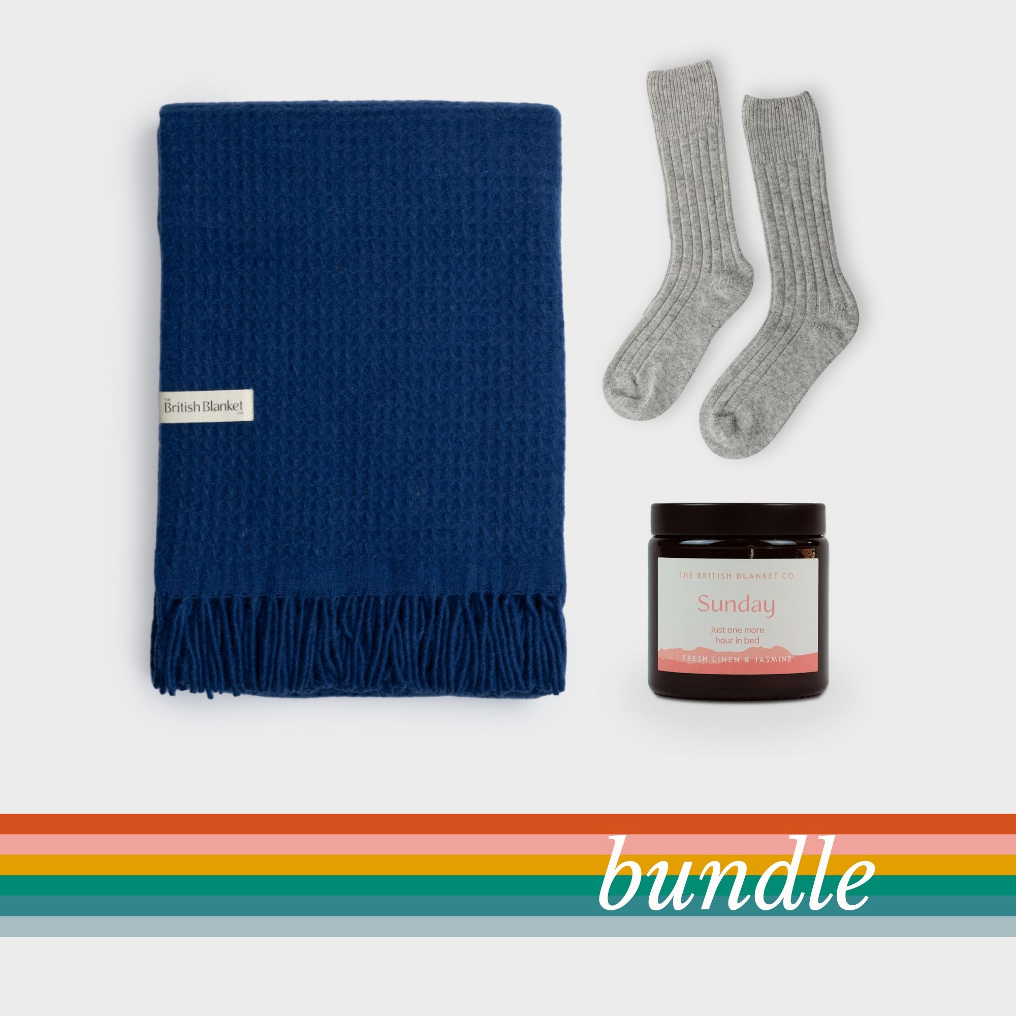 Bright Friday Blanket Bundle: Curious features a deep-blue woven blanket, light-grey socks, and a Sunday candle, perfect for gifting or personal comfort.