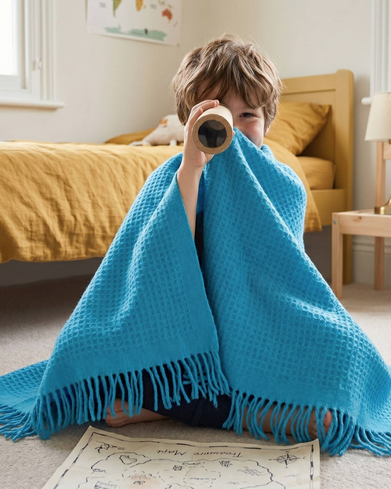 Child playing pirates in their bedroom with a Bright Blue Waffle Kids Blanket from the British Blanket company