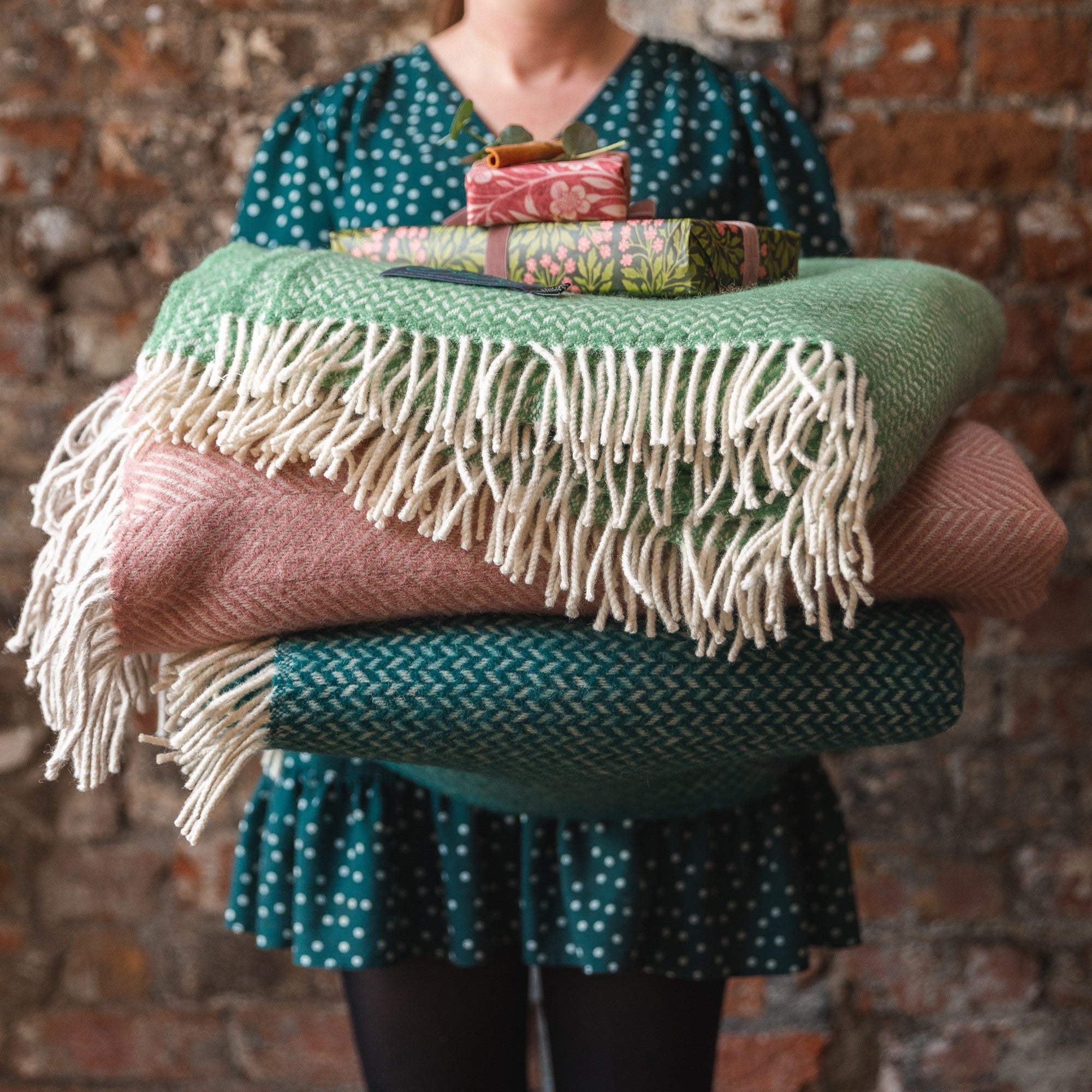 Woman holding stack of blankets. £10 off two large or XL blanket offer