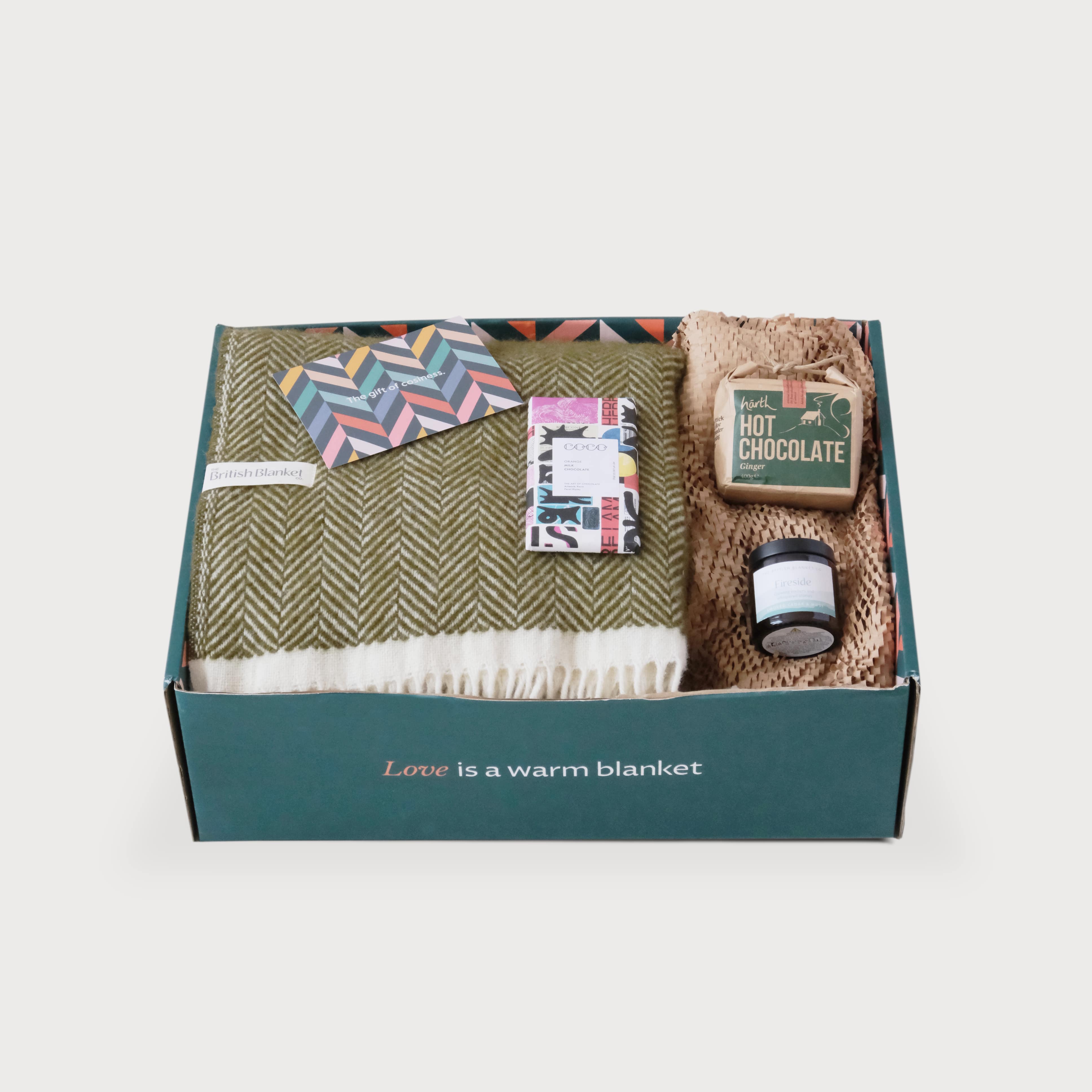 The Christmas Blanket Gift Box: Blaise includes a British Blanket, enclosure card, COCO chocolate, ginger hot chocolate, and Fireside candle, nestled in kraft paper.