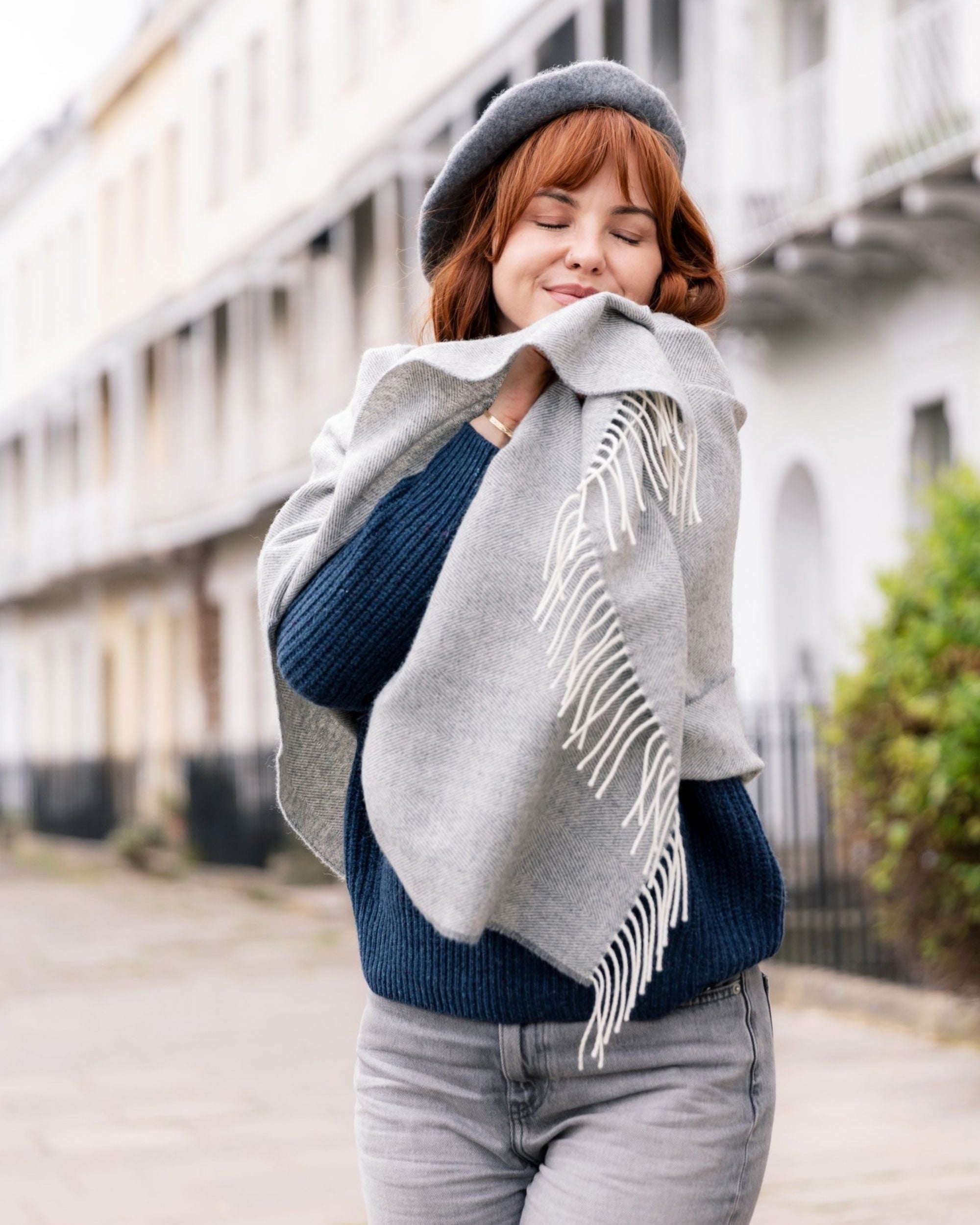 Woman wearing a gray merino scarf with white fringe outdoors