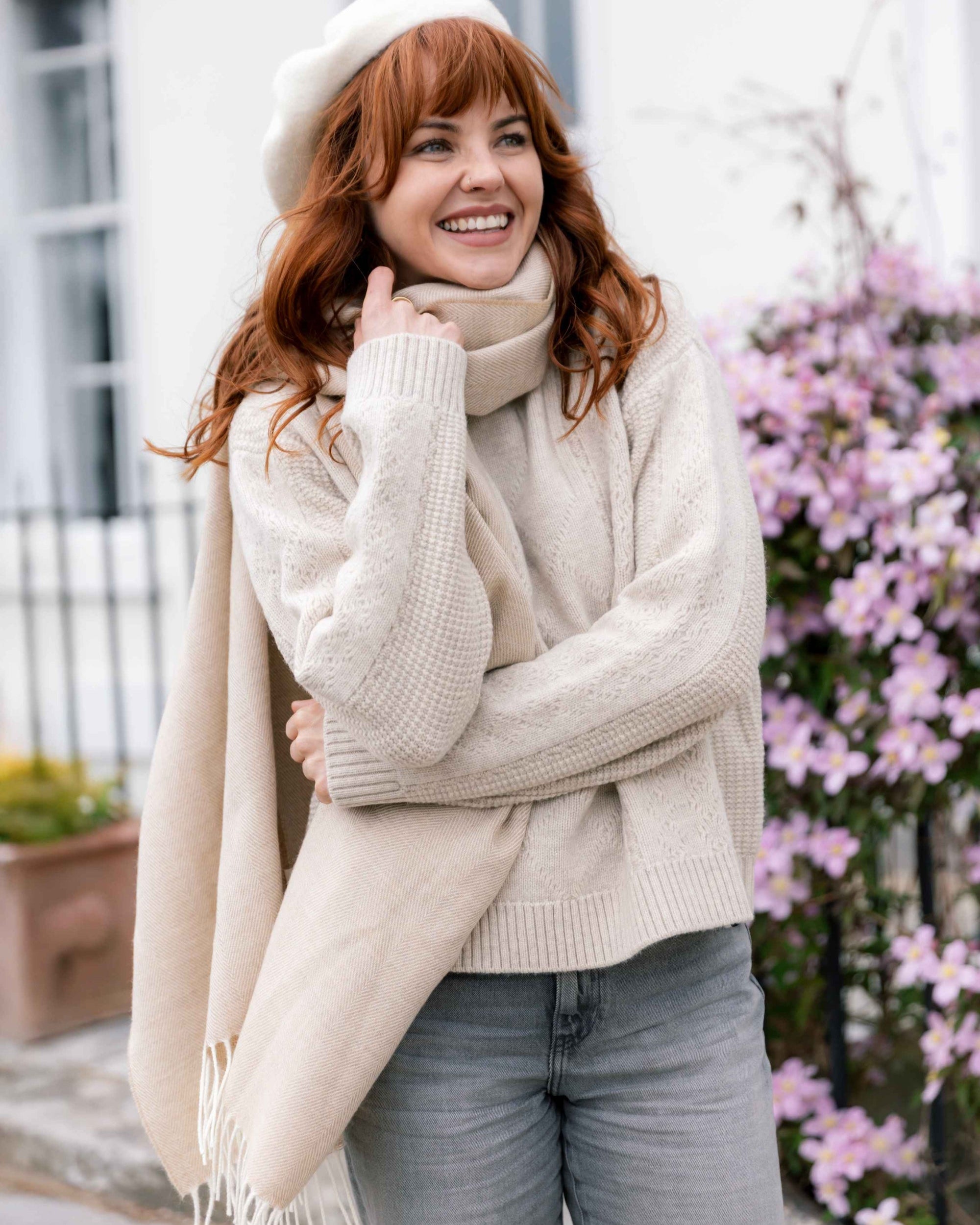 Young woman wearing the Oversized Blanket Scarf Gift Box: Basswood Herringbone, draped around her neck, paired with a beret, smiling outdoors.