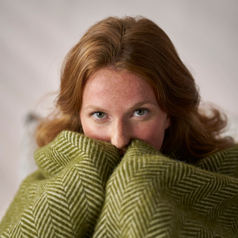 A close up of a woman wrapped in the Clifton Blaise Herringbone Blanket