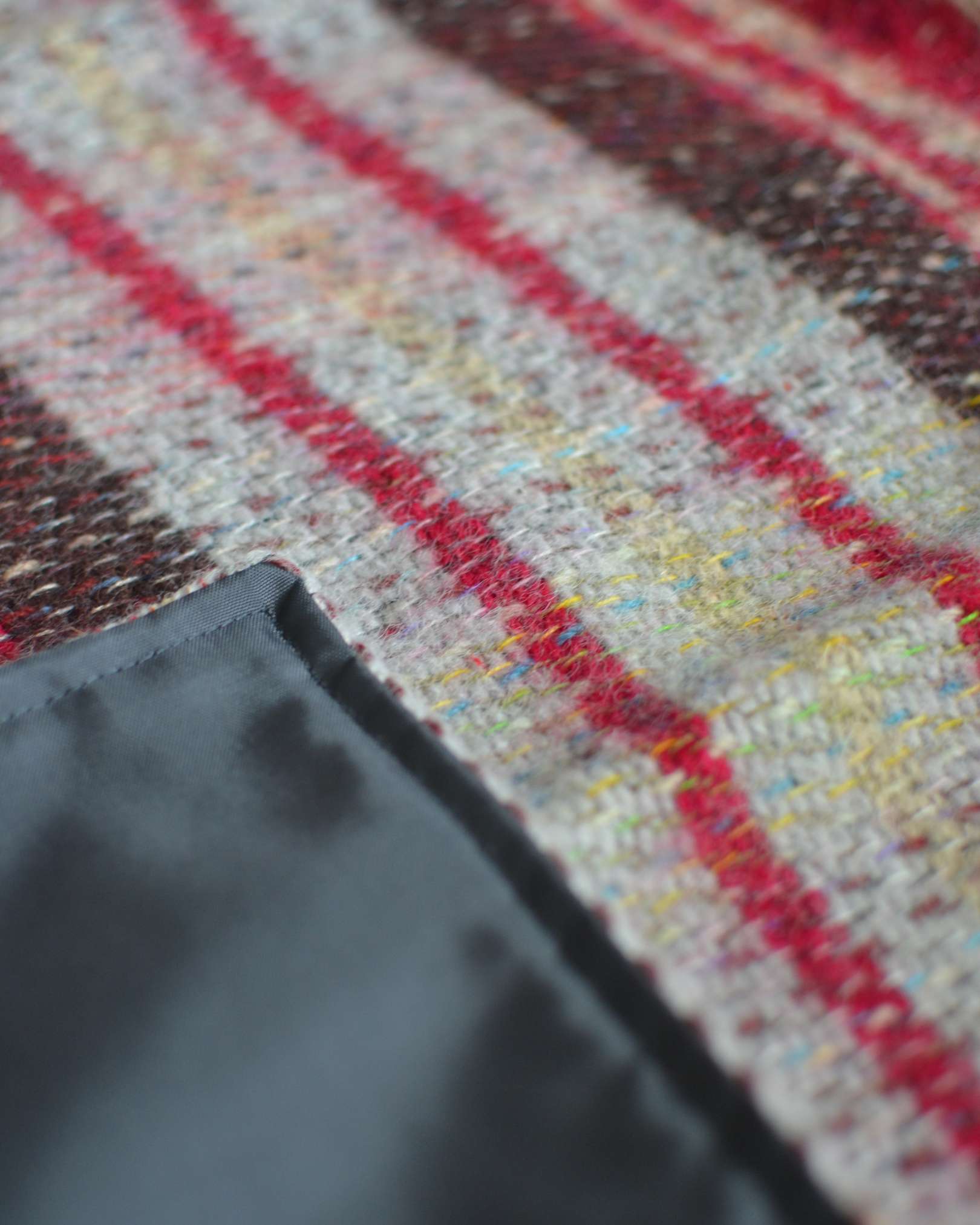 Close-up of a fabric with red and yellow plaid pattern on a textured surface.