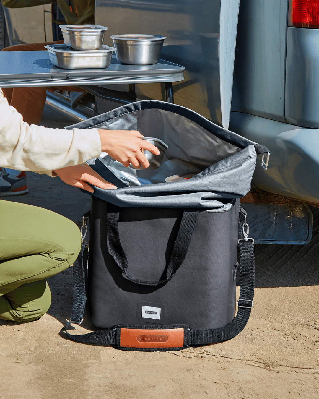 Person packing up the Black + Blum Cooler bag with Lunch box collection