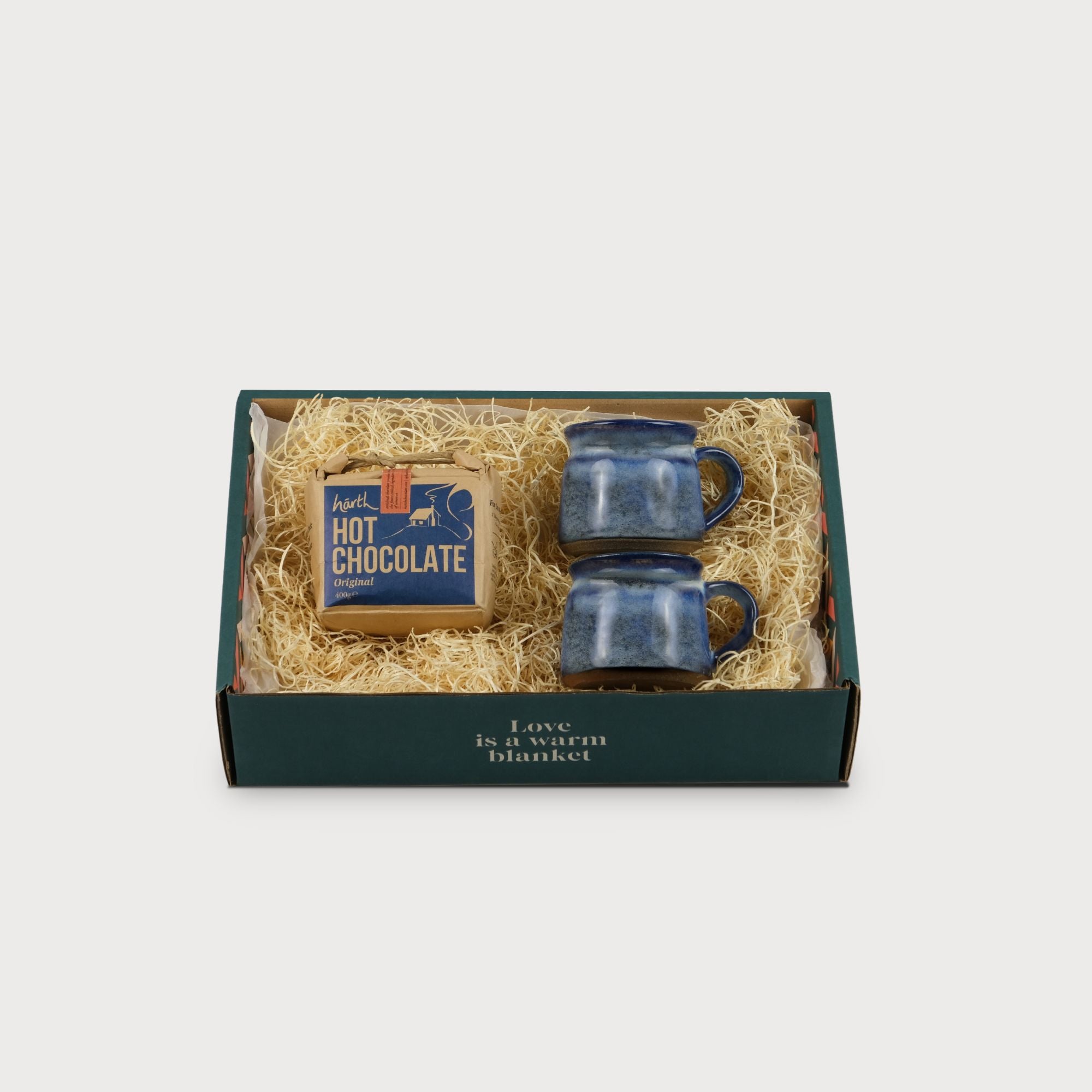 Cosy Gift Box: Snuggle Together featuring a package of hot chocolate and a box with blue mugs, ideal for cozy moments.