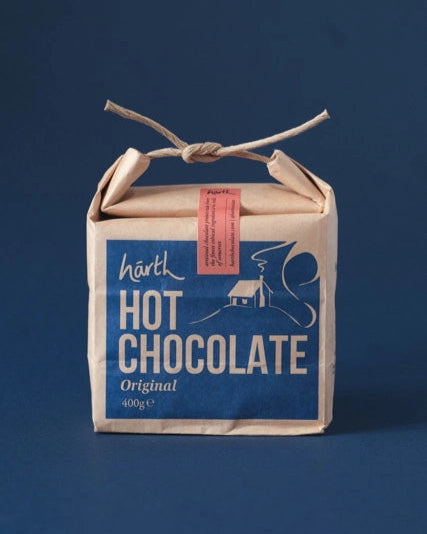 Artisan Ginger Hot Chocolate in a 400 g natural-kraft pouch with rope-tie, featuring a blue label. Organic blend for a velvety, indulgent drink.