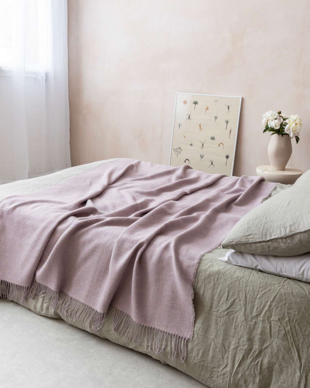 Alpaca Blanket Gift Box: Heather Pink displayed in a serene bedroom, featuring a woven throw on the bed, complementing the calming decor.