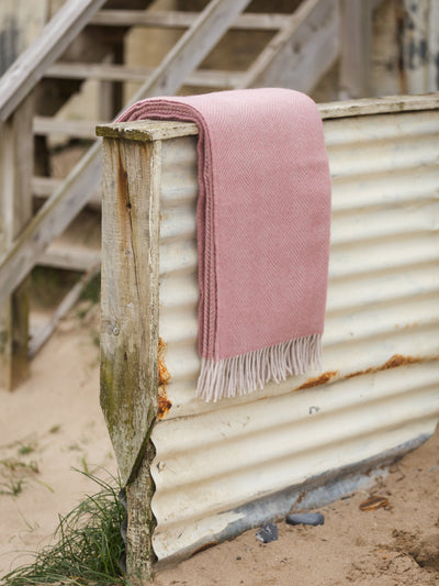 dusky pink herringbone throw on a fence at the beach from The British Blanket Company