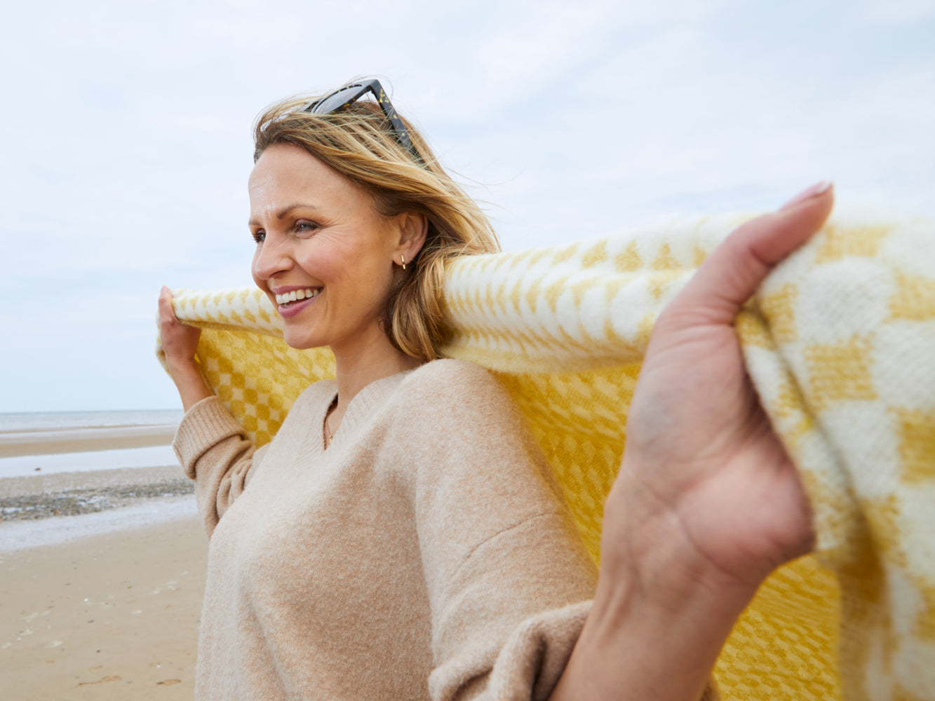 woman on the beach with yellow jacquard check wool throw from the british blanket company