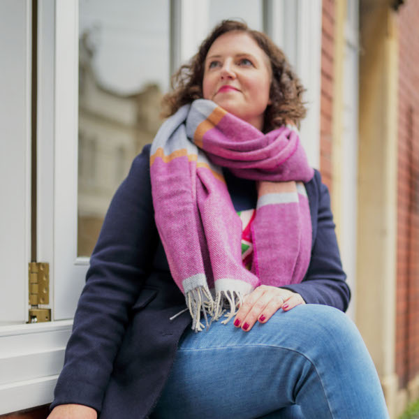 Woman wearing pink wool blanket scarf from The British Blanket Company