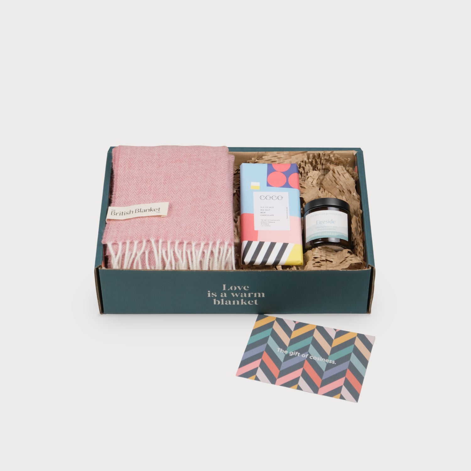Scarf Gift Box: Blossom Herringbone featuring a pink wool blanket, sea salt chocolate, a scented candle, and a chevron gift card, ideal for cozy evenings.