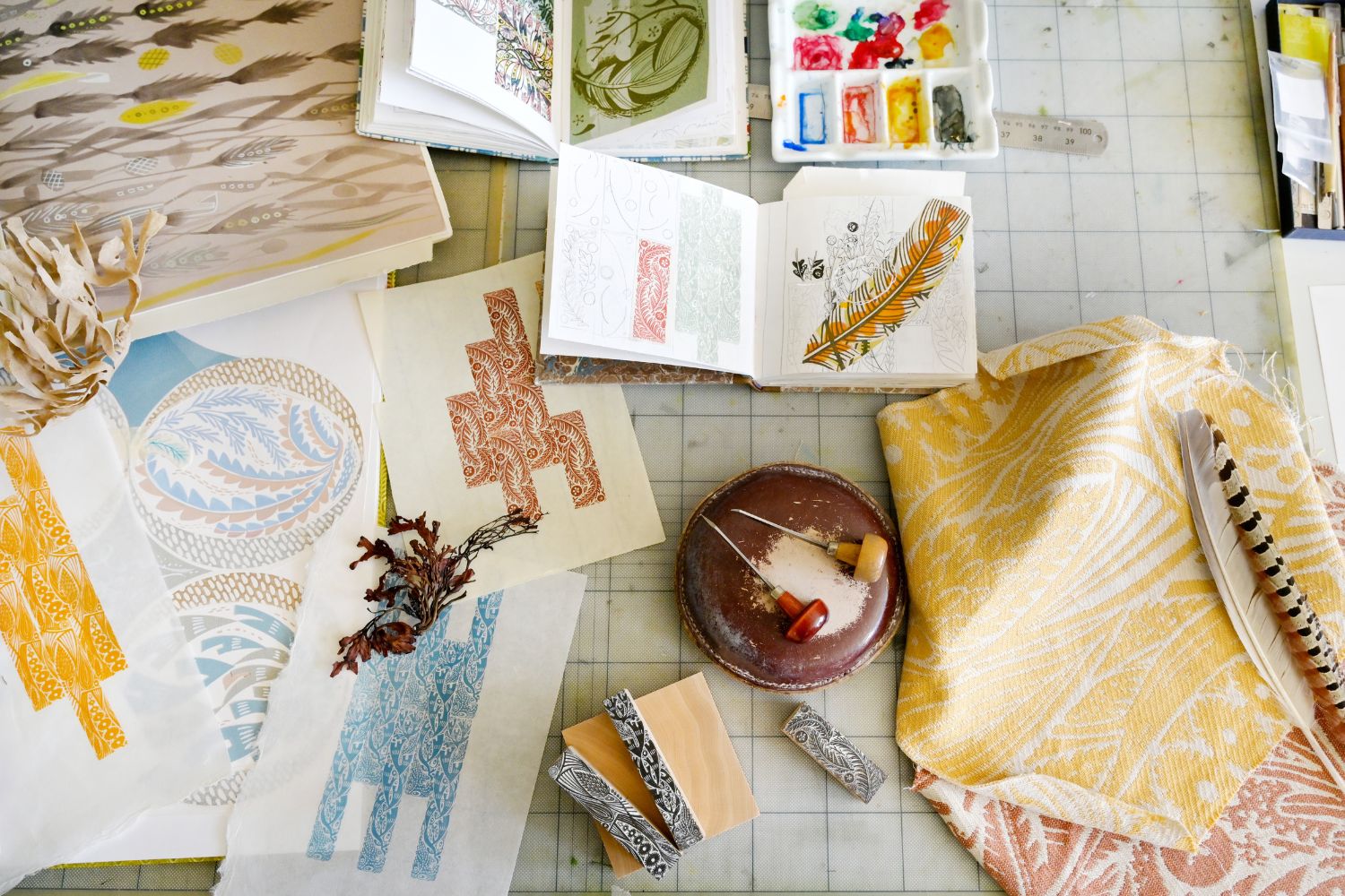Angie Lewin's work table, covered in test prints, sketchbooks, and fabric samples.