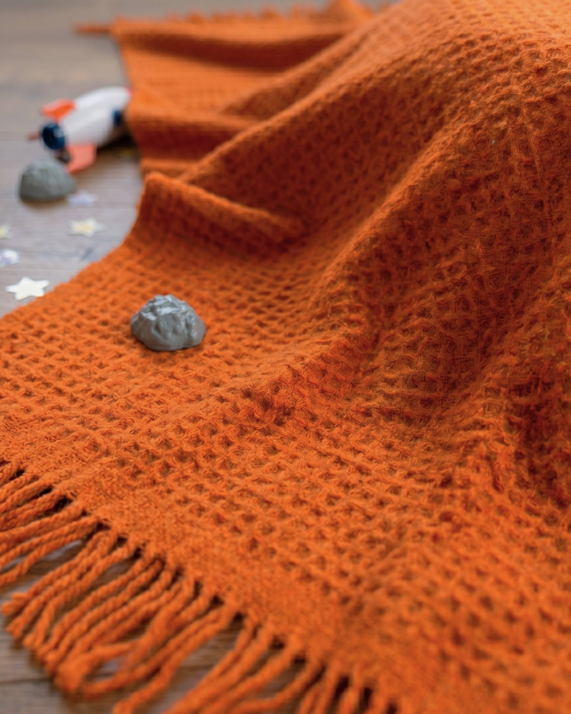 Close up of childrens space toys on orange waffle blanket