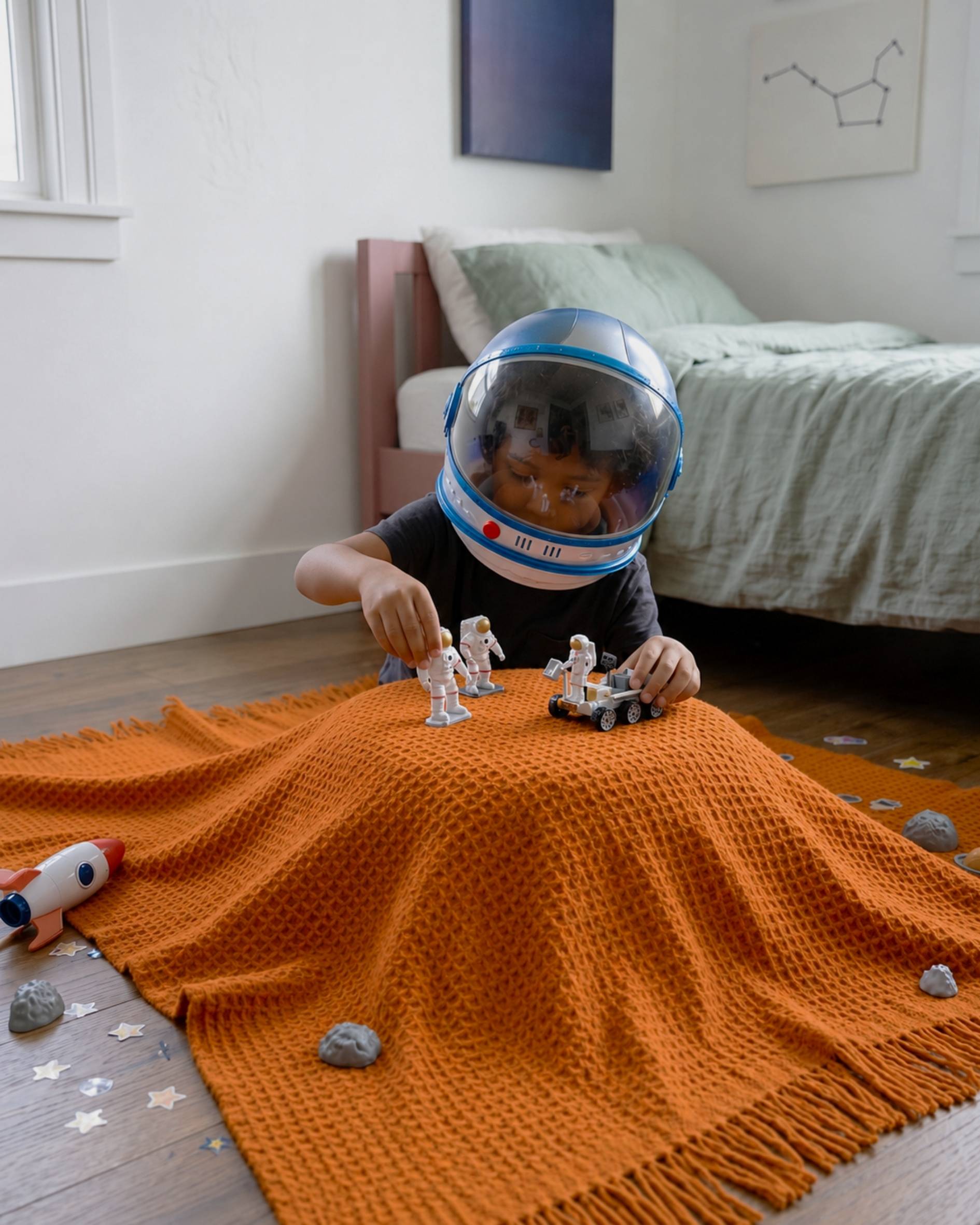 Young boy playing with space toys on orange waffle blanket