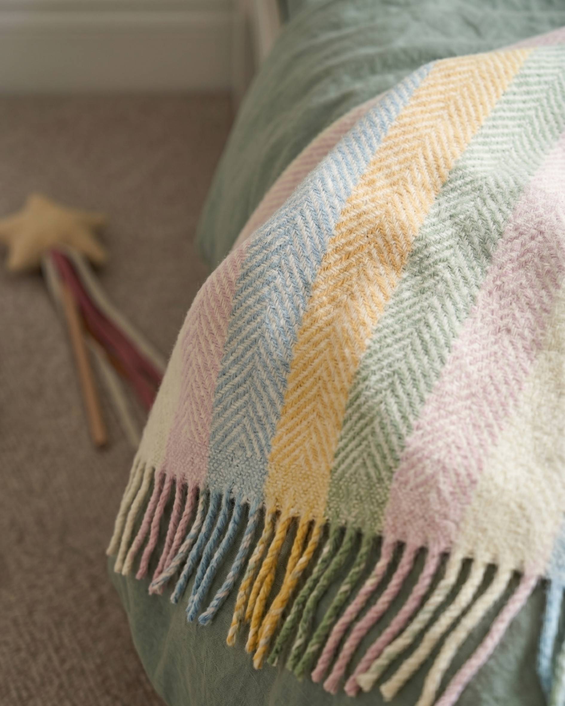 Pastel rainbow stripe blanket draped over a childs bed