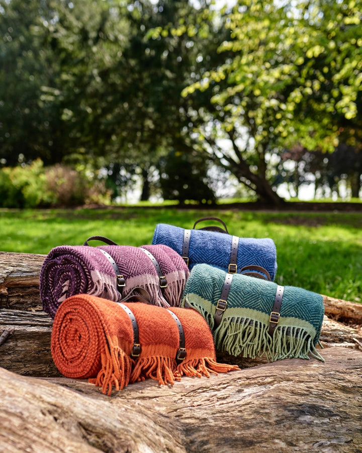 Purple wool picnic blanket rolled up with leather carry straps