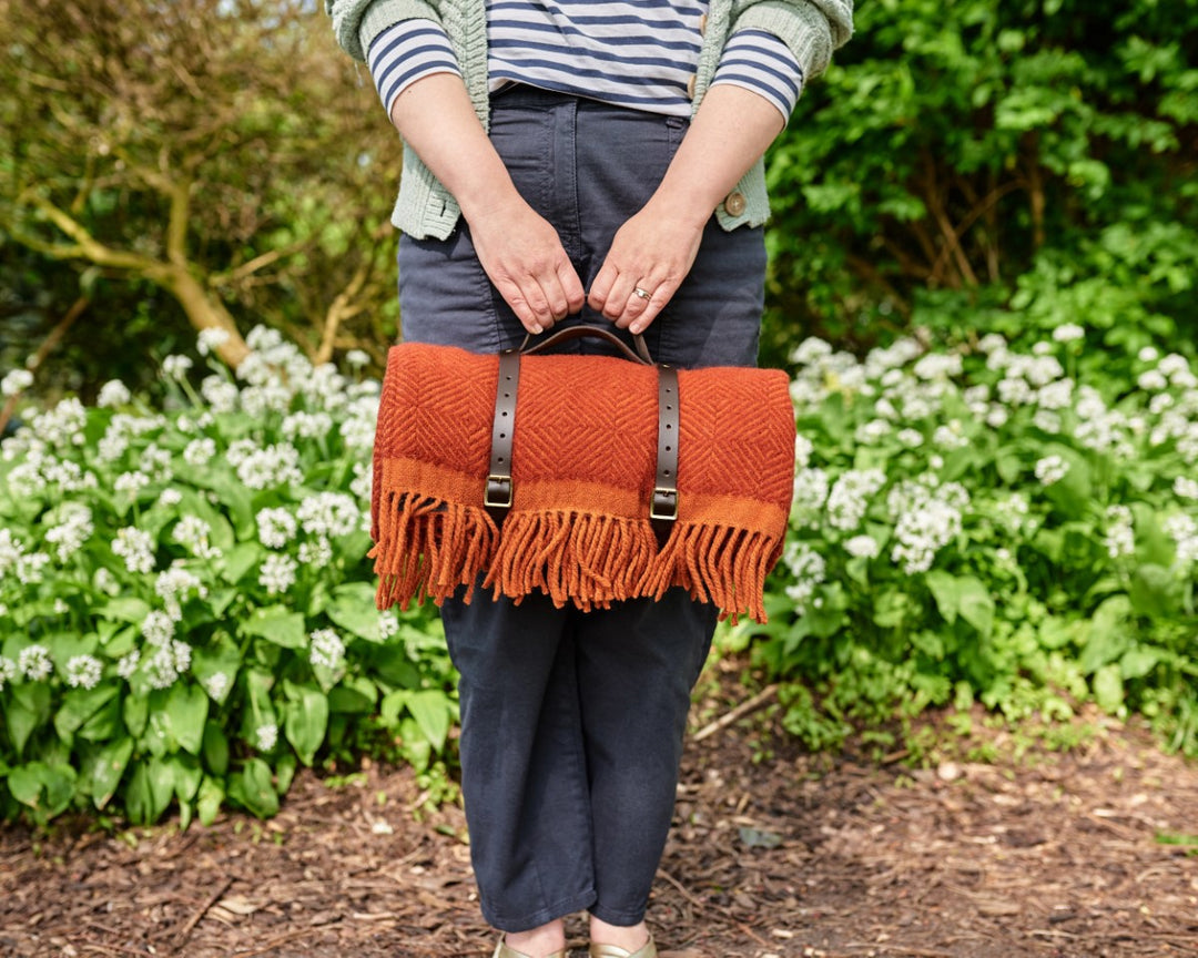 Red wool picnic blanket rolled up with leather carry straps