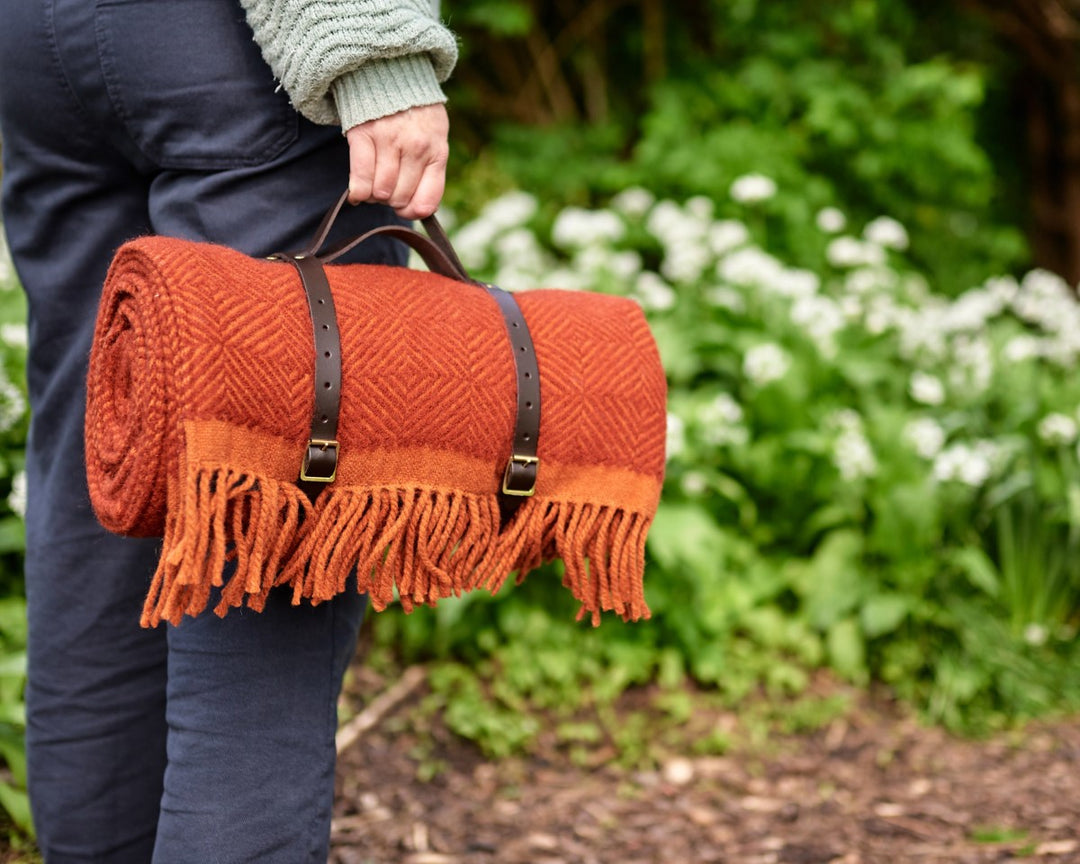 Red wool picnic blanket rolled up with leather carry straps