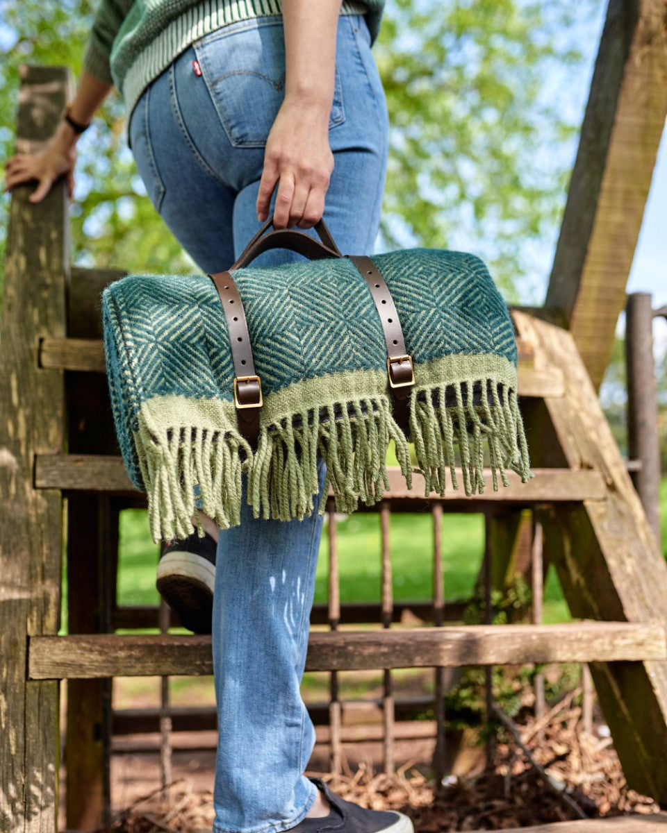 Green wool picnic blanket rolled up with leather carry straps