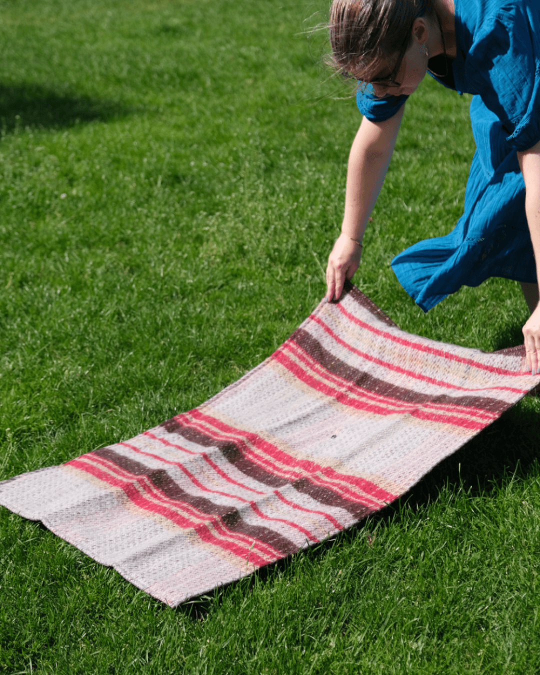 Person setting up a waterproof picnic mat in the park
