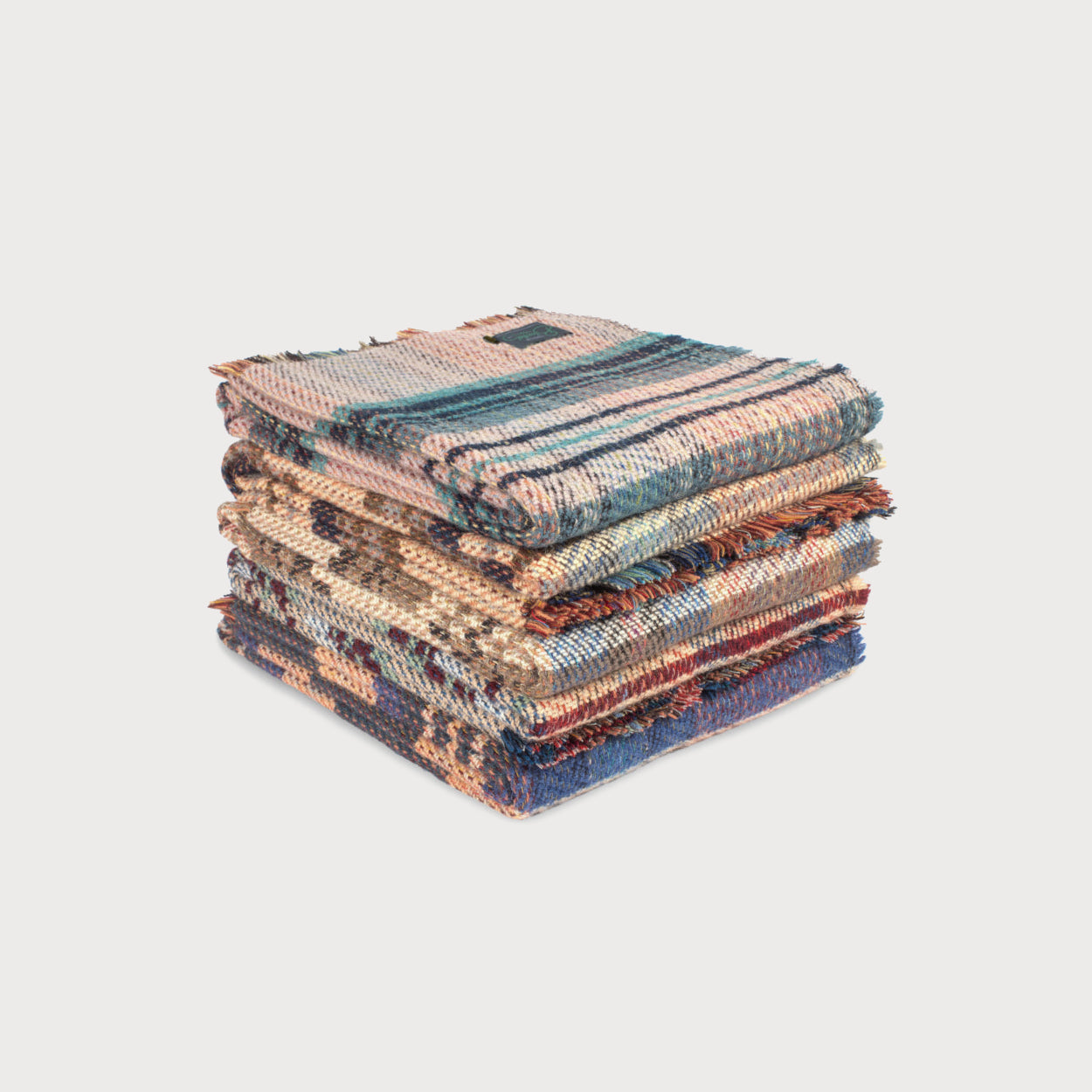 Stacked Cosy Gift Set: Dog Blanket & Toy showcasing woven throws with varied patterns and fringed edges, against a light background.