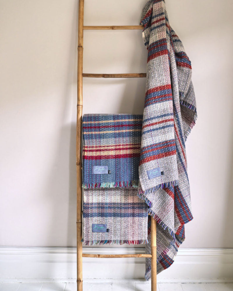 Cosy Crew Reward: 3 For 2 Random Recycled (Small) displayed on a natural-wood ladder; three woven throws draped, showcasing sustainable, upcycled wool craftsmanship.