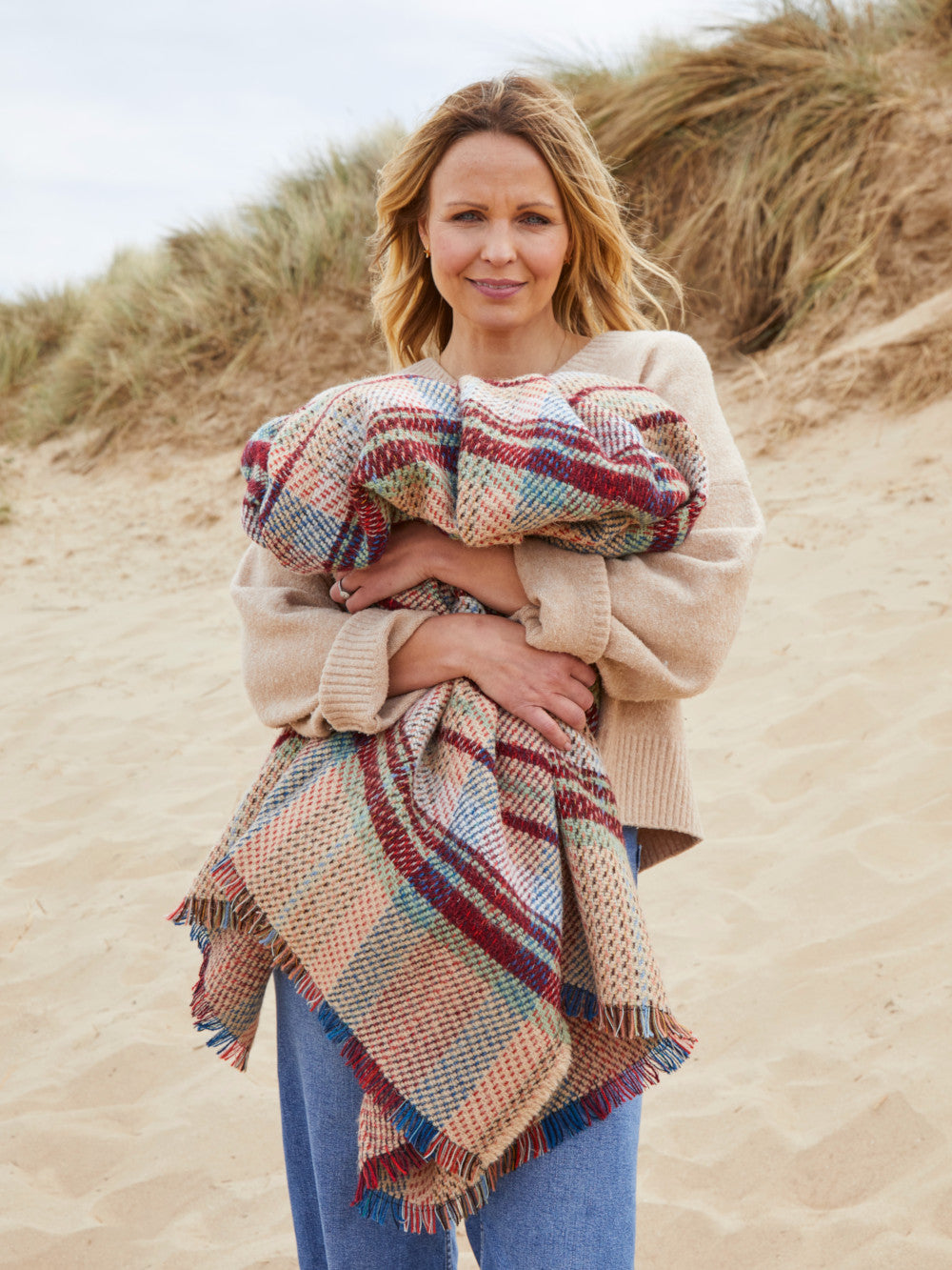 woman on the beach holding a Random recycled wool throw blanket - The British Blanket Company