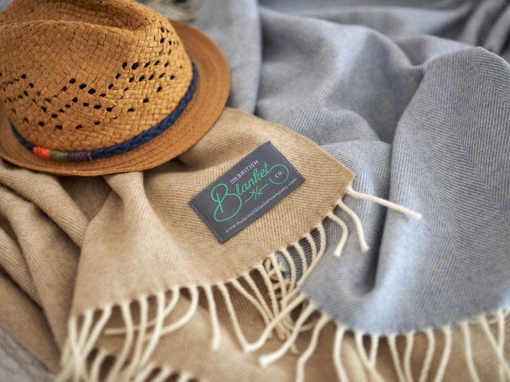 blue and beige wool blankets on a bed with straw hat