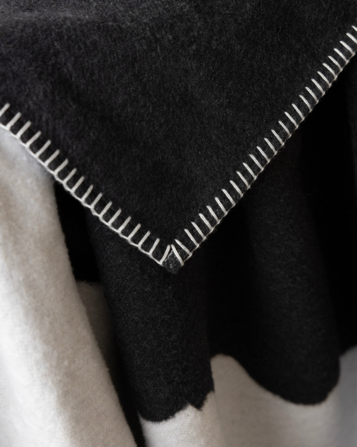 Cloud Cotton Blanket: Strata in Flint, showcasing a two-tone design with a soft, fuzzy texture and contrasting whip-stitched edge, made from recycled cotton.